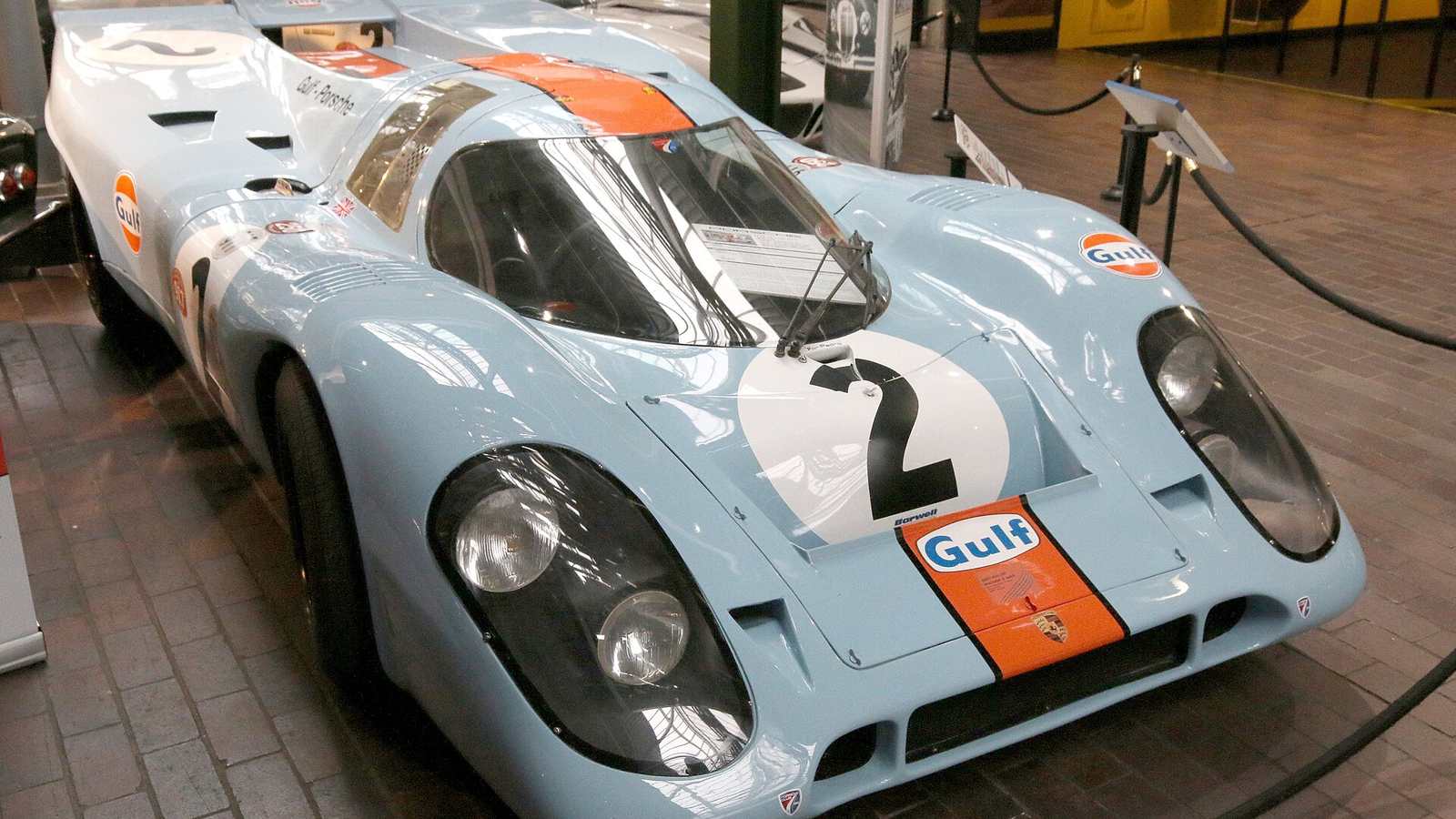 A Porsche 917 K in pale blue and orange Gulf colours on display in a museum