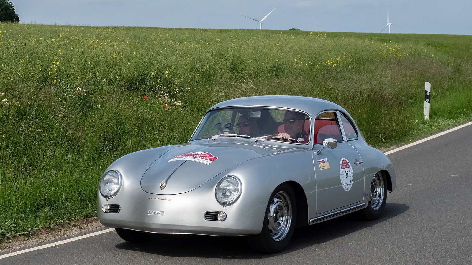 A silver Porsche 356 A coupé on a country road during a classic car rally