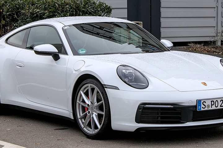 A white Porsche 911 Carrera S of the 992 generation parked in a car park