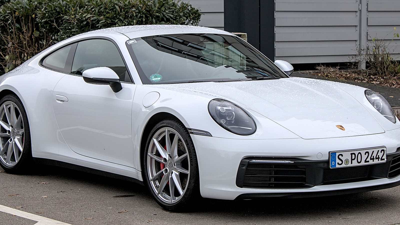 A white Porsche 911 Carrera S of the 992 generation parked in a car park