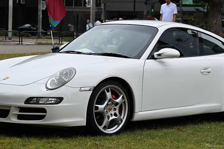 A white Porsche 911 Carrera S of the 997 generation parked on grass