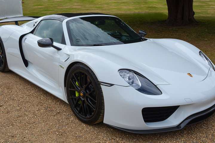 A white Porsche 918 Spyder parked on gravel