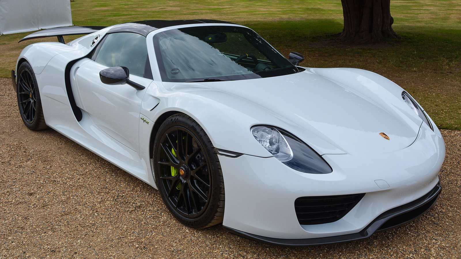 A white Porsche 918 Spyder parked on gravel