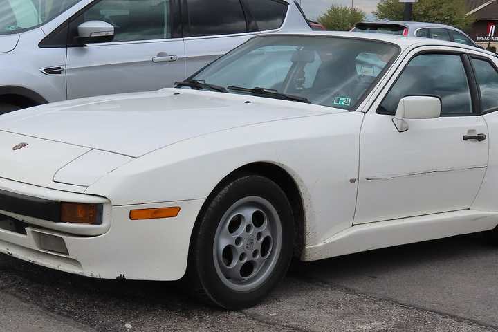 A white Porsche 944 coupé parked in a car park