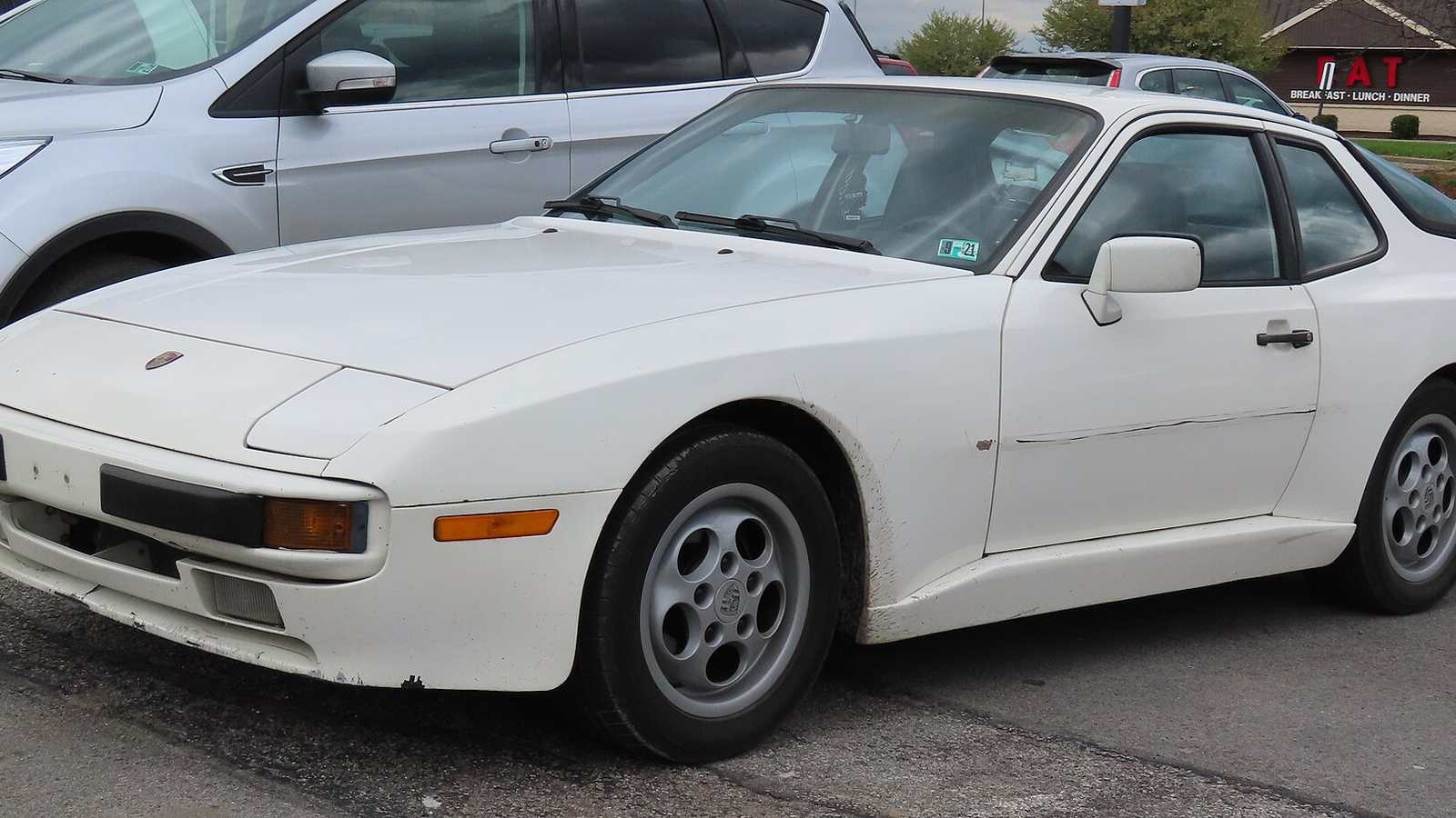 A white Porsche 944 coupé parked in a car park