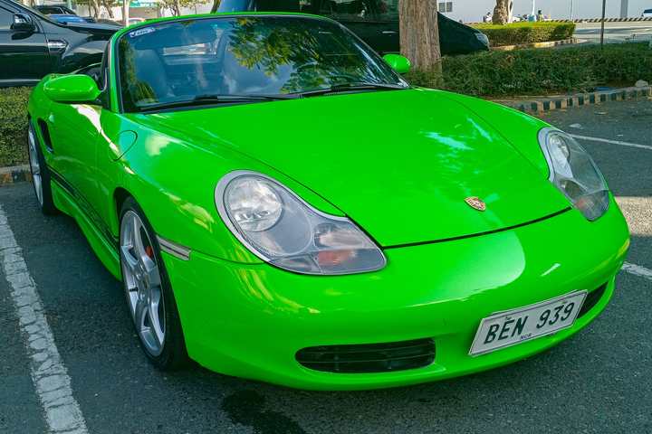 A bright green Porsche Boxster of the 986 generation parked in a car park