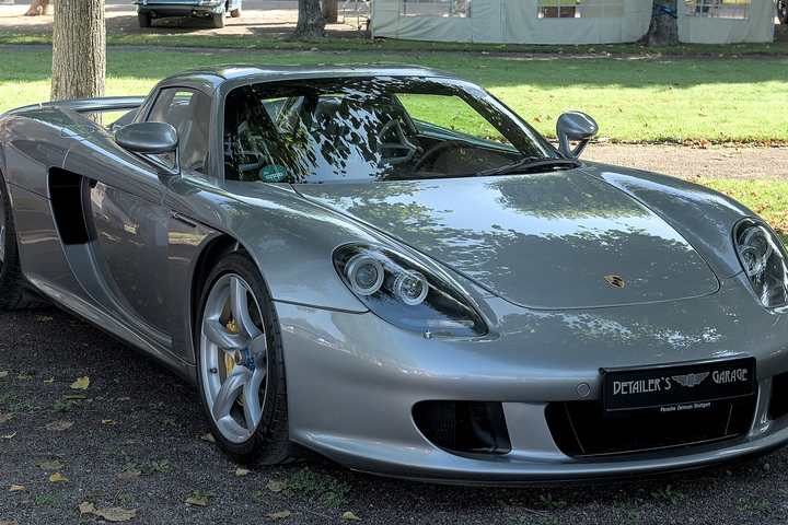 A silver Porsche Carrera GT parked on grass at a classic car event